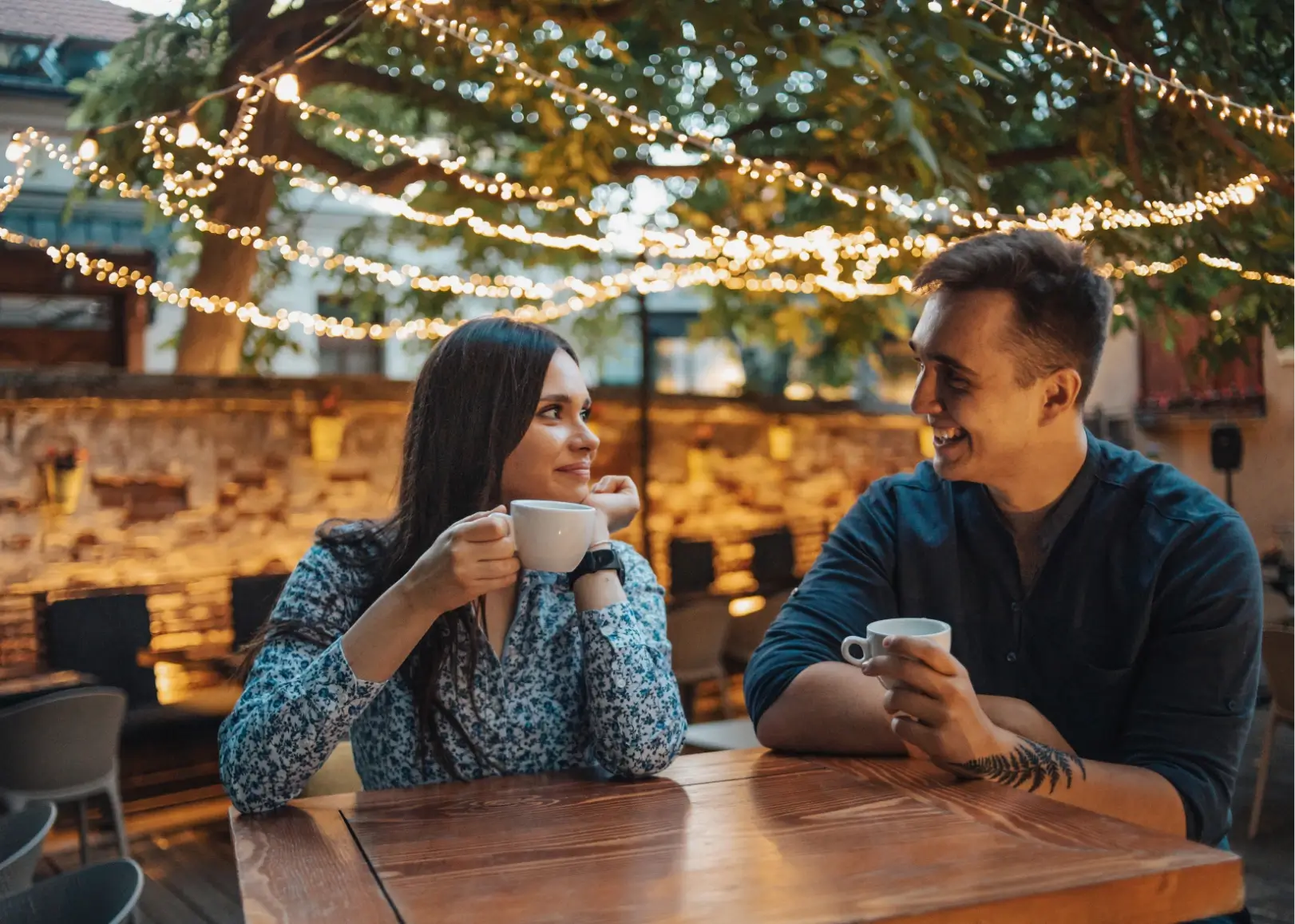 Paar genießt Kaffee unter Lichterketten in gemütlichem Wiener Gastgarten.