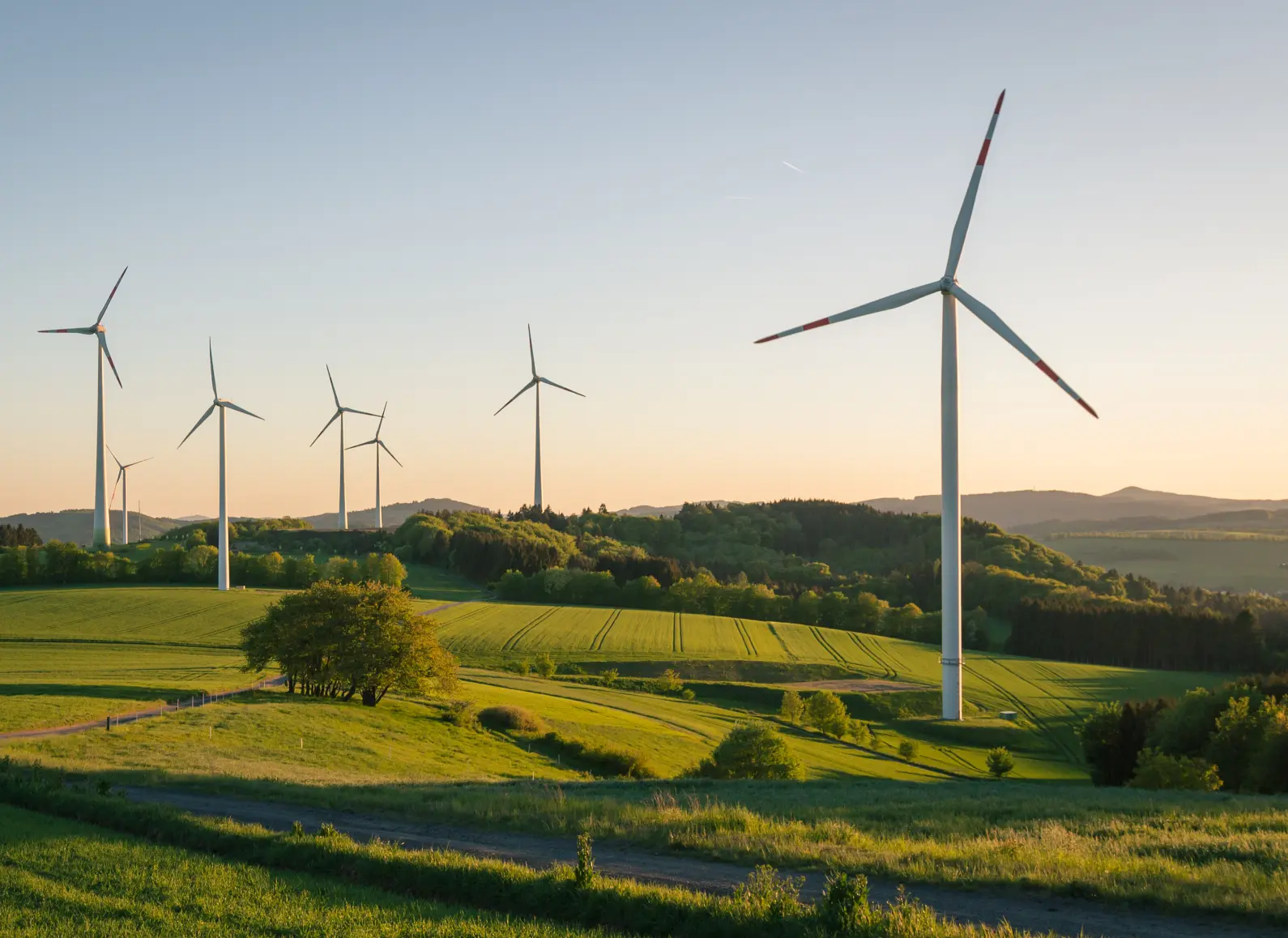 Windräder in sanfter Hügellandschaft bei Sonnenuntergang nahe Wien.